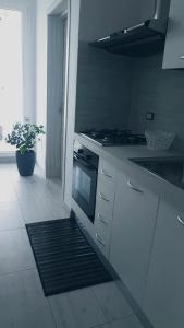 una cucina bianca con piano cottura e lavandino di B&BWHITE a Ugento