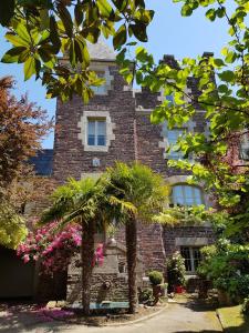 a brick building with palm trees in front of it at Castel Jolly in Rennes