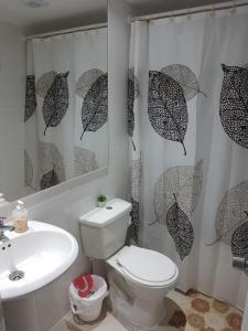 a bathroom with a toilet and a sink and umbrella shower curtain at Departamento Alejandra in El Tabo