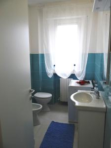 a bathroom with a toilet and a sink and a window at Luminoso Appartamento al mare in Martinsicuro