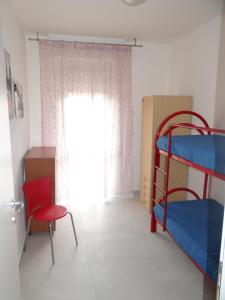 Zimmer mit 2 Etagenbetten und einem roten Stuhl in der Unterkunft Luminoso Appartamento al mare in Martinsicuro