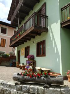 a building with a balcony and a table and flowers at B&B Le Fontane Fam. Degan in Carzano