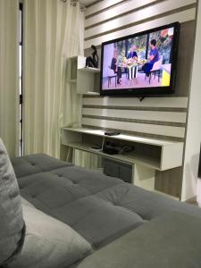 a living room with a television on a wall at Apartamento 401 Edificio London in Piratuba