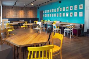 a dining room with wooden tables and yellow chairs at Hostel Marmota in Innsbruck