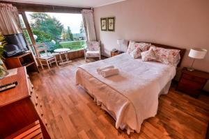 a bedroom with a bed and a large window at Hotel y Cabañas El Parque in Villarrica