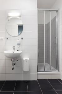 a white bathroom with a sink and a shower at Hostel Marmota in Innsbruck