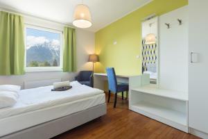 a room with a bed, chair, lamp and a window at Hostel Marmota in Innsbruck
