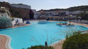 una gran piscina azul con sillas y edificios en Condominio Le Palme en Santa Teresa Gallura