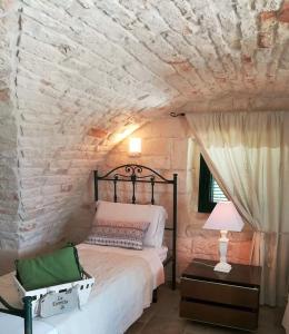 a bedroom with a bed and a stone wall at Maison MilleOttocento in Cisternino