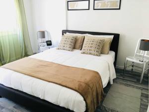 1 dormitorio con 1 cama grande con sábanas y almohadas blancas en Cheerful Apartment in Nicosia en Yukarı Lakatamya