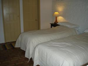 two beds in a room with a lamp on a table at Top Parts Bed & Breakfast in Abbotsbury