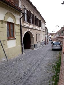 a cobblestone street next to a building with a car at Traditional Hermannstadt in Sibiu