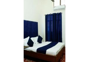 a bedroom with a bed with blue curtains at Inderlok Hotel in Chandīgarh