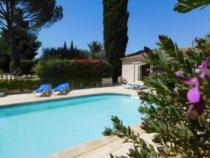 a swimming pool with two blue chairs and a house at Les Bougainvillées de Camargue in Villetelle