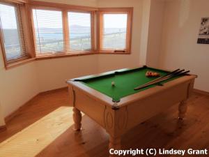 una mesa de billar verde en una habitación con ventanas en Quoys Self Catering en Lerwick