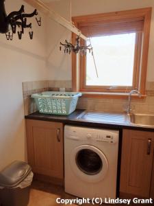 a kitchen with a washing machine and a window at Quoys Self Catering in Lerwick