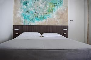 a bed in a bedroom with a painting on the wall at Hotel Muccioli in Misano Adriatico