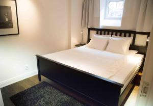 1 dormitorio con 1 cama grande con sábanas y almohadas blancas en Executive Living Östermalm Suite, en Estocolmo