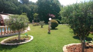 un jardin avec des arbres et une statue sur l'herbe dans l'établissement Chambre et table d'hôtes Villa Pomponette, à Nans-les-Pins