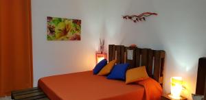 una camera da letto con letto con lenzuola arancioni e cuscini blu di B&B CARRUBBELLE a Ragusa