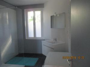 een badkamer met een wastafel, een toilet en een raam bij Appartement Bord de Mer in Locquirec