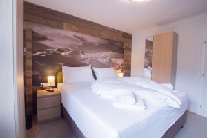 ein Schlafzimmer mit einem großen weißen Bett mit einem Gemälde an der Wand in der Unterkunft Arabella Seeappartements in Zell am See