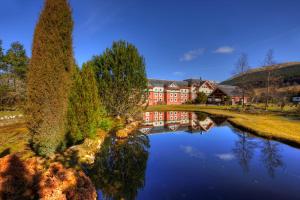 a large building with a reflection in the water at Muthu Ben Doran Hotel in Tyndrum