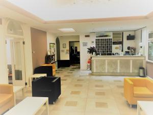 a lobby of a salon with yellow chairs and a counter at Hotel Al Mare in Lido di Jesolo