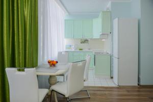 a kitchen with green curtains and a table and chairs at Sea View Odessa in Odesa