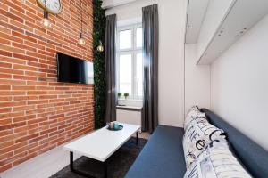 ein Wohnzimmer mit Sofa und Ziegelwand in der Unterkunft Dietla 99 - Studio by Homeprime in Krakau