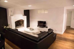 sala de estar con sofá negro y chimenea en Executive Living Östermalm Suite, en Estocolmo