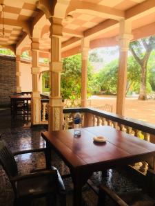drewniany stół i krzesła na ganku w obiekcie New Land Guest House w mieście Pasikuda