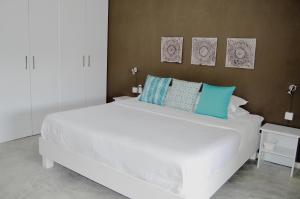 - une chambre avec un grand lit blanc et des oreillers bleus dans l'établissement Summerdays Studios, à Coteau Raffin