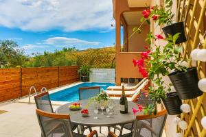a patio with a table and chairs and a swimming pool at Apartmani Ana in Kaštela