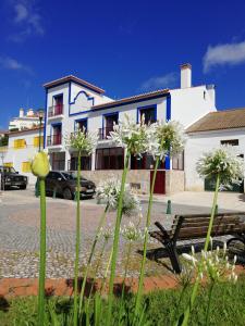 a bench in front of a building with white flowers at Sol Mar in Odeceixe