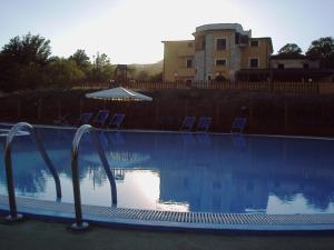 a swimming pool with chairs and a building in the background at Hotel Borgo Antico in San Severino