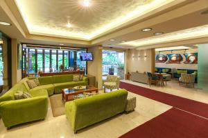 a living room with green couches and a table at Paradise Lost Hotel-Apartments in Tolo