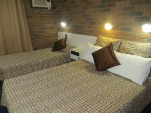 two beds with pillows in a hotel room at Cattleman's Rest Motor Inn in Charters Towers