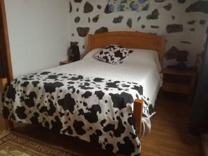 a bed with a black and white cow print sheets at AL - Adega do Terra in Madalena