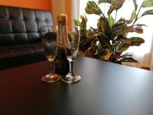 two wine glasses sitting on a table next to a plant at Karingo House in Fratta Polesine