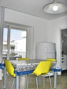 una cucina con tavolo, sedie gialle e frigorifero di Casa Alice Vista Mare a Marina di Ragusa