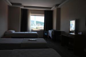 a hotel room with two beds and a window at Helenapolis Otel in Altınova