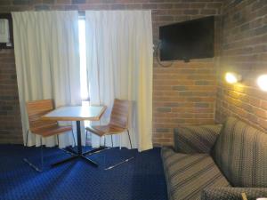 a room with a table and chairs and a tv at Cattleman's Rest Motor Inn in Charters Towers