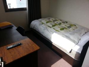 a bed in a room with a table and a remote control at Hotel Wakasato in Nagano