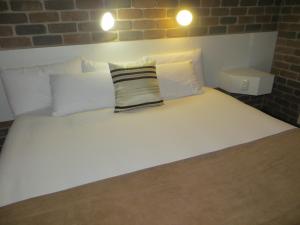 a white bed with two pillows on top of it at Cattleman's Rest Motor Inn in Charters Towers