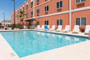 
a swimming pool with chairs and tables in front of a building at Amelia Hotel at the Beach in Fernandina Beach
