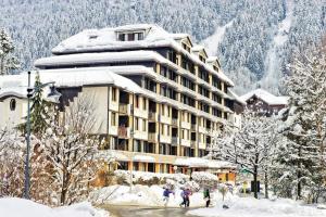 un hotel en la nieve con gente caminando delante de él en Chamois Blanc, en Chamonix-Mont-Blanc