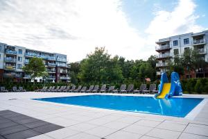 a swimming pool with chairs and a slide at LATO apartament Polanki Park z miejscem parkingowym in Kołobrzeg