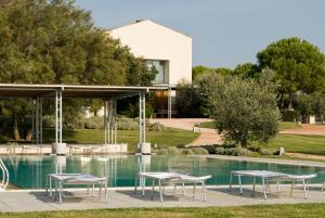 a pool with tables and chairs next to a building at Casale del Mare in Castiglioncello