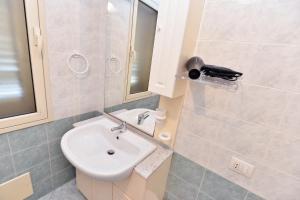ein Badezimmer mit einem Waschbecken, einem WC und einem Spiegel in der Unterkunft IzzHome Regina Margherita in Pula